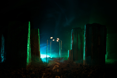 Empty street of burnt up city, flames on the ground and blasts with smoke in the distance. Apocalyptic view of city downtown as disaster film poster concept. Night scene. City destroyed by war.の写真素材