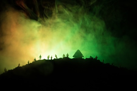 Scary view crowd of zombies on hill with spooky cloudy sky with fog and rising full moon. Silhouette group of zombie walking under full moon. Halloween concept.の写真素材