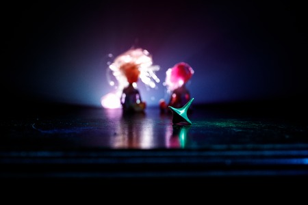 Totem spinning top spinning, wobbling and stopping. Spinning top on mirror surface with toned smoke background light. Whirligig in action in dark room on table. Selective focusの写真素材