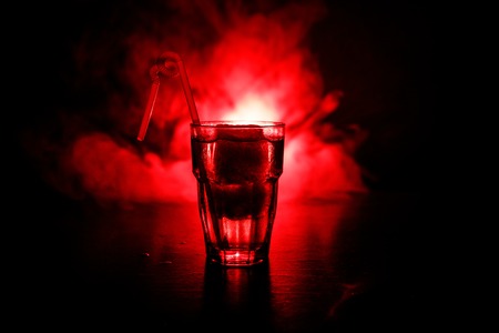 Alcohol cocktail in glass with ice in smoke on dark toned background. Club drinks concept. One glass of cocktailの写真素材