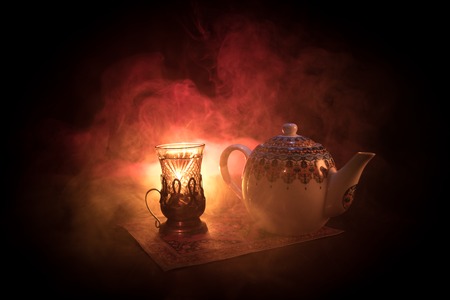 Eastern tea in traditional glasse and pot on black background with lights and smoke. Eastern tea concept. Armudu traditional Azerbaijan/Turkish cup. Selective focus. Glass of Teaの写真素材
