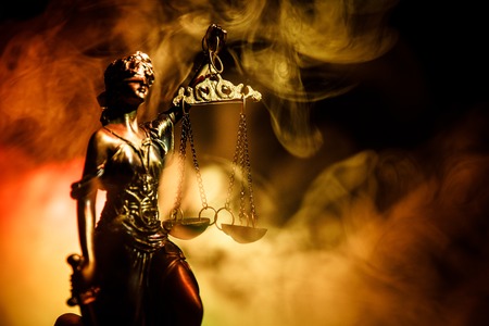 The Statue of Justice - lady justice or Iustitia / Justitia the Roman goddess of Justice on a dark fire background. Selective focusの写真素材