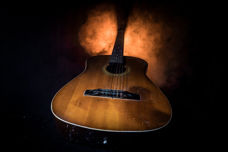Music concept. Acoustic guitar on a dark background under beam of light with smoke. Guitar with Strings, close up. Selective focus. Fire effects.の写真素材
