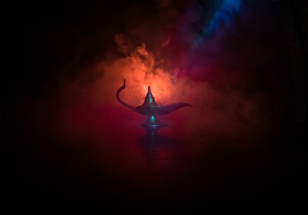Antique Aladdin arabian nights genie style oil lamp with soft light white smoke, Dark background. Lamp of wishes concept. Selective focusの写真素材