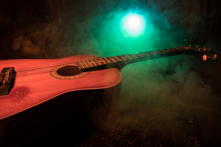 Music concept. Acoustic guitar on a dark background under beam of light with smoke. Guitar with Strings, close up. Selective focus. Fire effects.の写真素材
