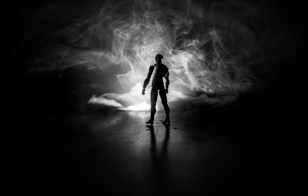 Silhouette of man standing on an dark foggy toned background. Decorated photo with man figure on table with light. Selective focusの写真素材