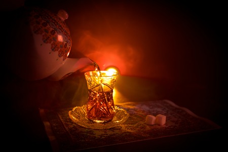 Eastern tea in traditional glasse and pot on black background with lights and smoke. Eastern tea concept. Armudu traditional Azerbaijan/Turkish cup. Selective focus. Glass of Teaの写真素材