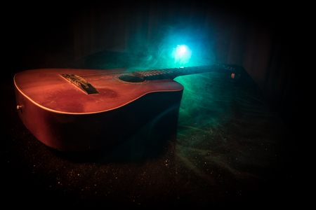 Music concept. Acoustic guitar on a dark background under beam of light with smoke. Guitar with Strings, close up. Selective focus. Fire effects.の写真素材