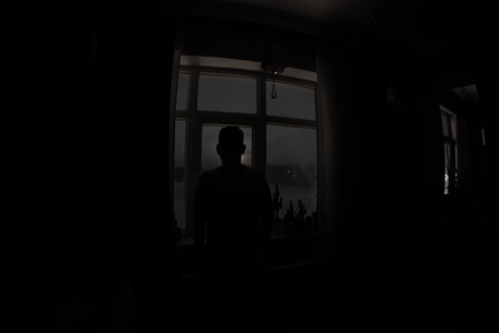 Night scene of moon seen through the window from dark room. Moonlight inside dark room. Moon over clouds view from dark roomの写真素材