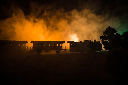 Train moving in fog. Ancient steam locomotive in night. Night train moving on railroad. toned foggy fire background. Horror mystical scene. Selective focusの写真素材