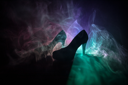 Black suede high heel women shoes on dark toned foggy background. Close up. Women power or women domination concept. Selective focusの写真素材