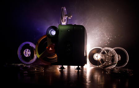 Old style movie projector, still-life, close-up. Film projector on a wooden background with dramatic lighting and selective focus. Movies and entertainment conceptの写真素材