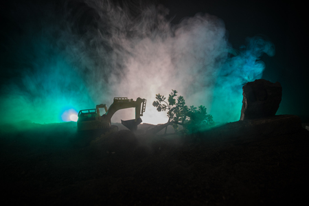 Deforestation of forest. Excavator used to dig up tree-stumps and roots after the forest was removed. Dark toned with fog table decoration. Conceptual. Selective focusの写真素材