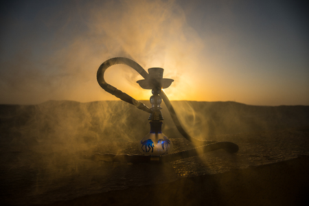 Hookah, traditional arabic waterpipe, direct sunset light, outdoor photo. Mountain background or...