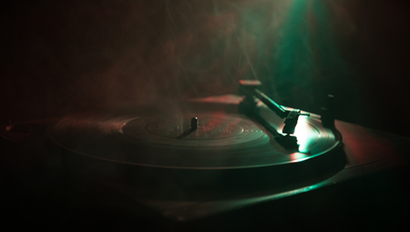 Turntable vinyl record player. Retro audio equipment for disc jockey. Sound technology for DJ to mix & play music. Vinyl record being played against burning fire background with smokeの写真素材