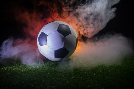 Traditional soccer ball on soccer field. Close up view of soccer ball (football) on green grass with dark toned foggy background. Selective focusの写真素材