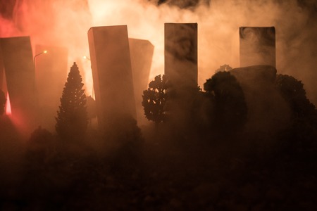 Empty street of burnt up city, flames on the ground and blasts with smoke in the distance. Apocalyptic view of city downtown as disaster film poster concept. Night scene. City destroyed by war.の写真素材