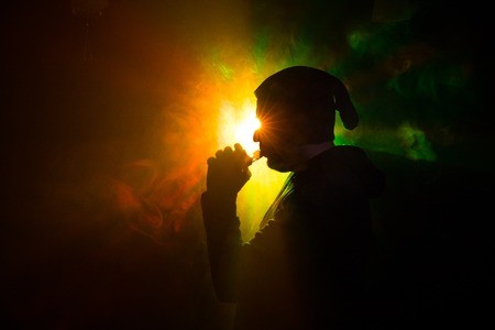 Vaping man holding a mod. A cloud of vapor. dark foggy toned background of clouds of smoke. Vaping...