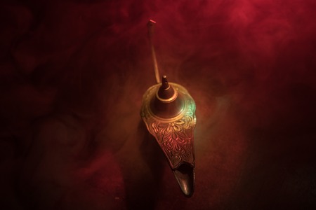 Antique Aladdin arabian nights genie style oil lamp with soft light white smoke, Dark background. Lamp of wishes concept. Selective focusの写真素材