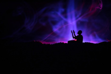 Silhouette of praying Muslim man on toned foggy background. Ramadan Kareem background. Muslim Eid...