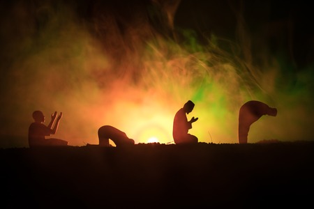 Silhouette of praying Muslim man on toned foggy background. Ramadan Kareem background. Muslim Eid...