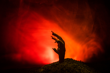 Halloween concept, zombie hand rising out from the ground or zombie hand coming out of his grave on dark toned foggy backgroundの写真素材