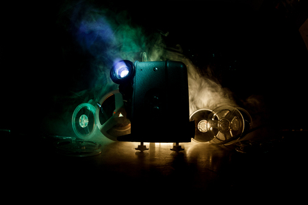 Old style movie projector, still-life, close-up. Film projector on a wooden background with dramatic lighting and selective focus. Movies and entertainment conceptの写真素材