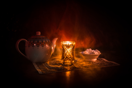 Eastern tea in traditional glasse and pot on black background with lights and smoke. Eastern tea concept. Armudu traditional Azerbaijan/Turkish cup. Selective focus. Glass of Teaの写真素材