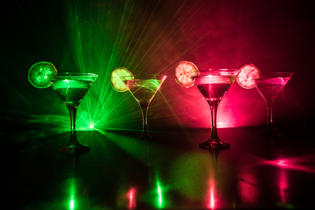 Several glasses of famous cocktail Martini, shot at a bar with dark toned foggy background and disco lights. Club drink concept. Selective focusの写真素材