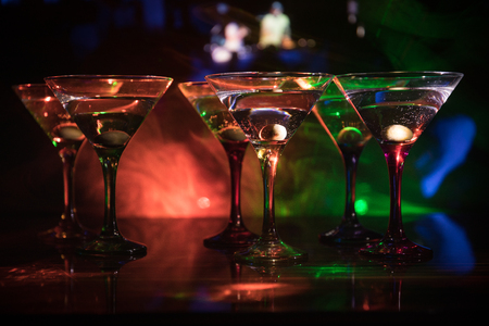 Several glasses of famous cocktail Martini, shot at a bar with dark toned foggy background and disco lights. Club drink concept. Selective focusの写真素材
