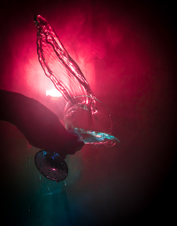 Martini cocktail glass in hand splashing on dark toned smoky background or colorful cocktail in glass with splashes and olives. Party club entertainment. Mixed light. Selective focusの写真素材