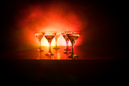 Several glasses of famous cocktail Martini, shot at a bar with dark toned foggy background and disco lights. Club drink concept. Selective focusの写真素材