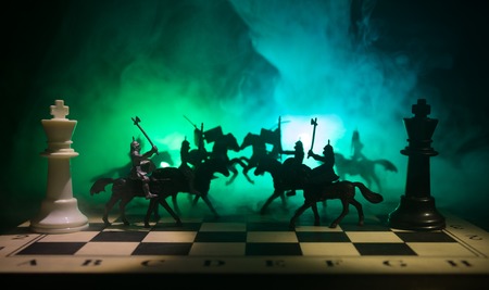 Medieval battle scene with cavalry and infantry on chessboard. Chess board game concept of business ideas and competition and strategy ideas Chess figures on a dark background with smoke and fog.の写真素材