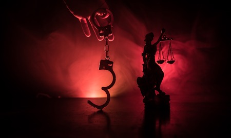 Legal law concept. Silhouette of handcuffs with The Statue of Justice on backside with the flashing...