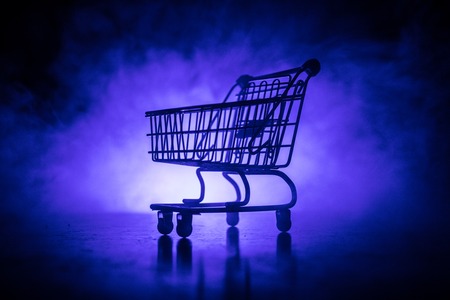 Empty shopping trolley on dark toned foggy background with some copy space. Financial crisis concept.の写真素材