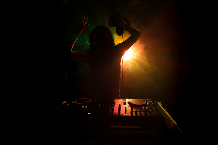 DJ Spinning, Mixing, and Scratching in a Night Club, Hands of dj tweak various track controls on...
