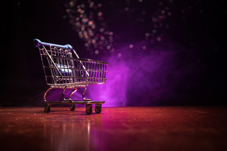 Empty shopping trolley on dark toned foggy background with some copy space. Financial crisis concept.の写真素材