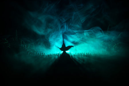 Lamp of wishes. Silhouette of a large crowd of people standing against a big lamp of wishes with toned light beams on foggy background. Dark night table decoration. Selective focusの写真素材