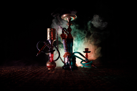 Hookah hot coals on shisha bowl making clouds of steam at Arabian interior. Oriental ornament on the carpet. Stylish oriental shisha in dark with backlight. For Shisha advertisement. Selective focusの写真素材