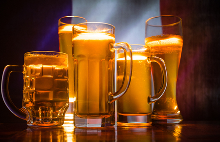 Creative concept. Beer glasses on table at dark toned foggy background with blurred view of flag of France. Support your country with beer concept. Selective focusの写真素材