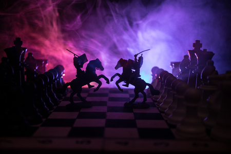 Medieval battle scene with cavalry and infantry on chessboard. Chess board game concept of business ideas and competition and strategy ideas Chess figures on a dark background with smoke and fog.の写真素材