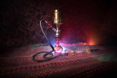 Hookah hot coals on shisha bowl making clouds of steam at Arabian interior. Oriental ornament on the...