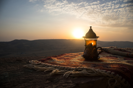 Eastern black tea in glass on a eastern carpet. Eastern tea concept. Armudu traditional cup. Sunset background. Selective focusの写真素材
