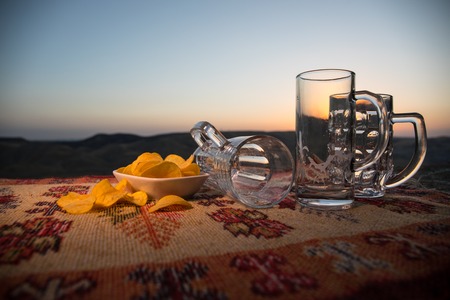 Close up empty mugs of beer on a sunrise background with mountains. Beer party is over concept. Selective focusの写真素材