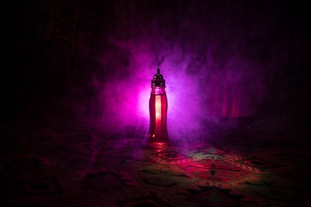 Antique and vintage glass bottle on dark foggy background with light. Poison or magic liquid concept.の写真素材
