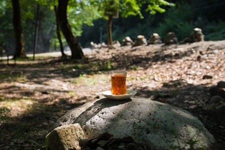 Eastern black tea in glass on a stone at forest. Eastern tea concept. Armudu traditional cup. Green...