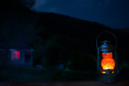 Horror Halloween concept. Burning old oil lamp in forest at night. Night scenery of a nightmare scene. Selective focus.の写真素材
