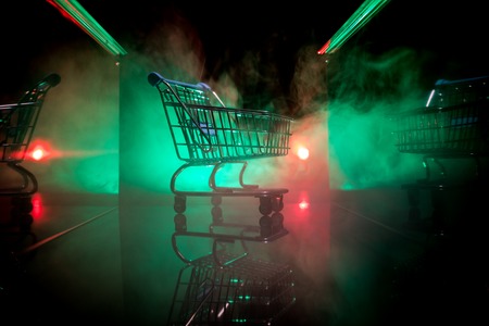 Empty shopping trolley on dark toned foggy background with some copy space. Financial crisis...