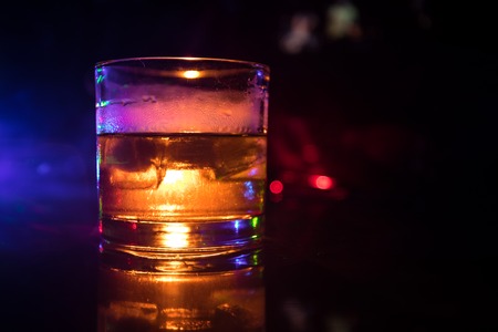 Selective focus pure whisky with ice cube inside whisky glass on dark foggy background alcohol drink concept. Close upの写真素材