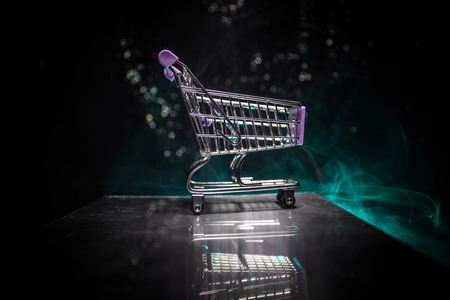 Empty shopping trolley on dark toned foggy background with some copy space. Financial crisis concept.の写真素材